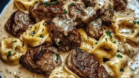 Delicious cracked garlic steak tortellini in creamy sauce on a plate.