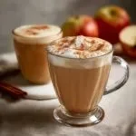 A warm cup of Apple Chai Latte garnished with apple slices and cinnamon