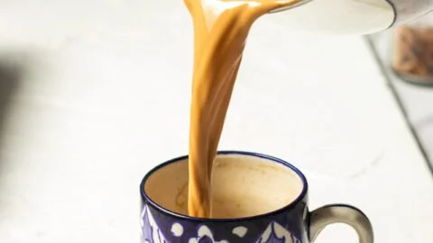 A cup of homemade milk tea with a teabag and milk on a table