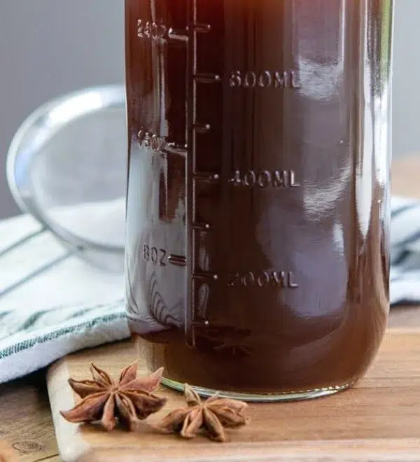 Homemade chai concentrate prepared in a kitchen with spices and tea leaves.
