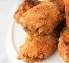A plate of homemade KFC-style chicken with crispy coating and herbs.