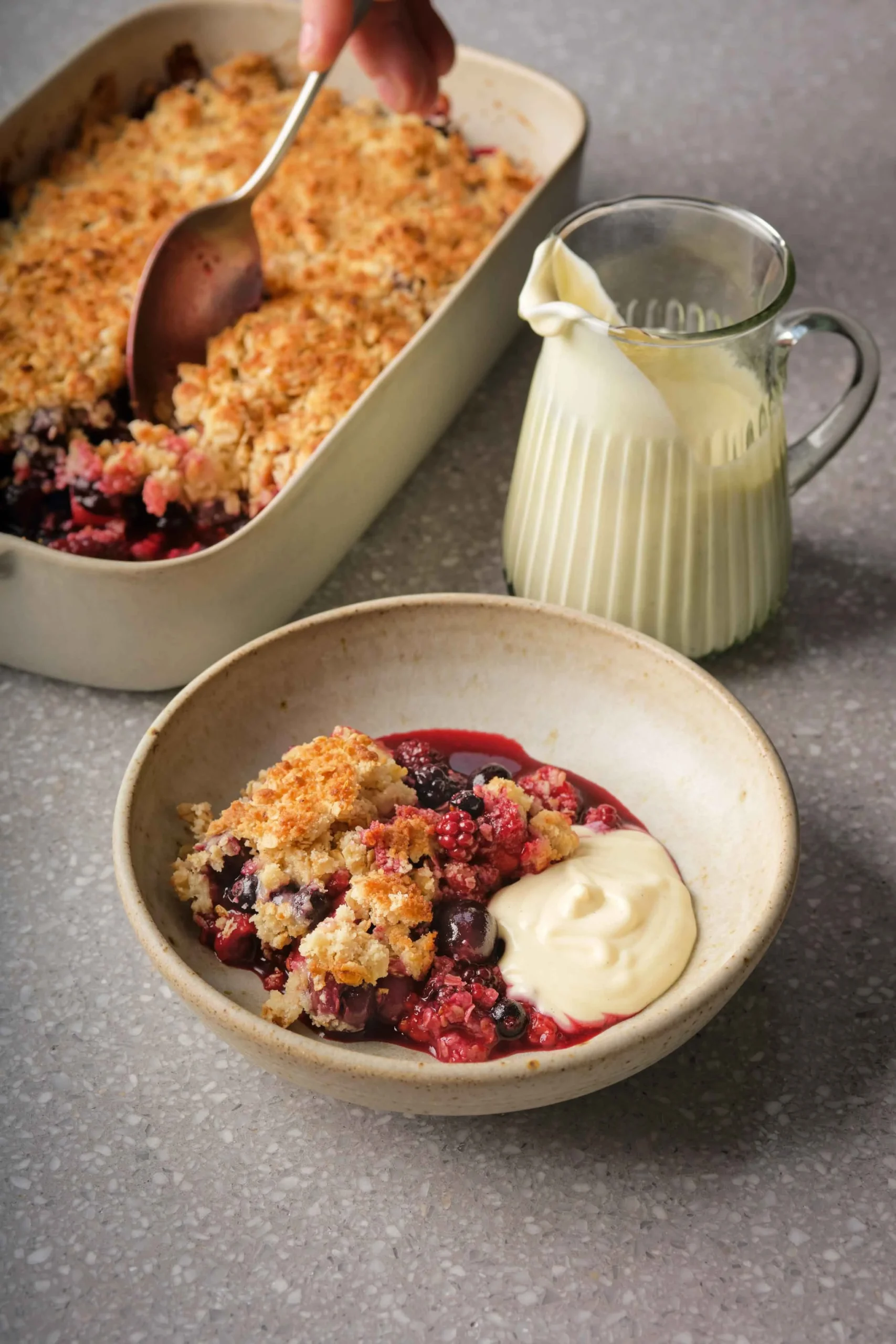 Bowl of Tom Kerridge's simple fruit crumble topped with fresh cream