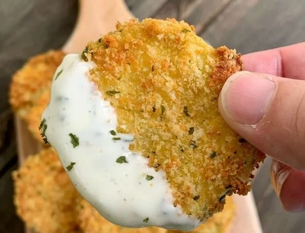 Crispy air fryer zucchini chips piled on a plate with seasoning