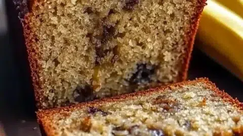 Deliciously moist banana bread slice with walnuts on a wooden table